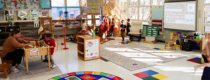 a wide shot of the lassroom, showing many children exploring different activity stations