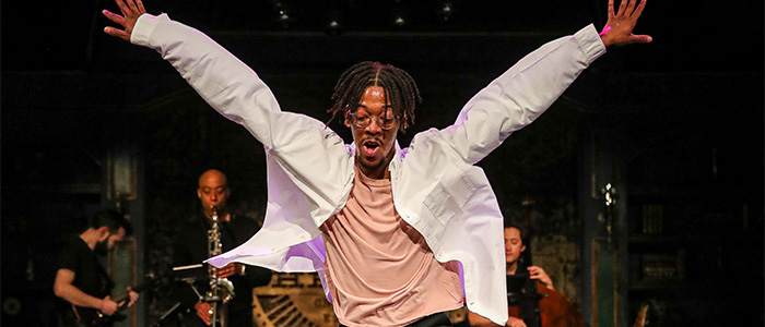 Man dances with arms outstretched upwards and to each side