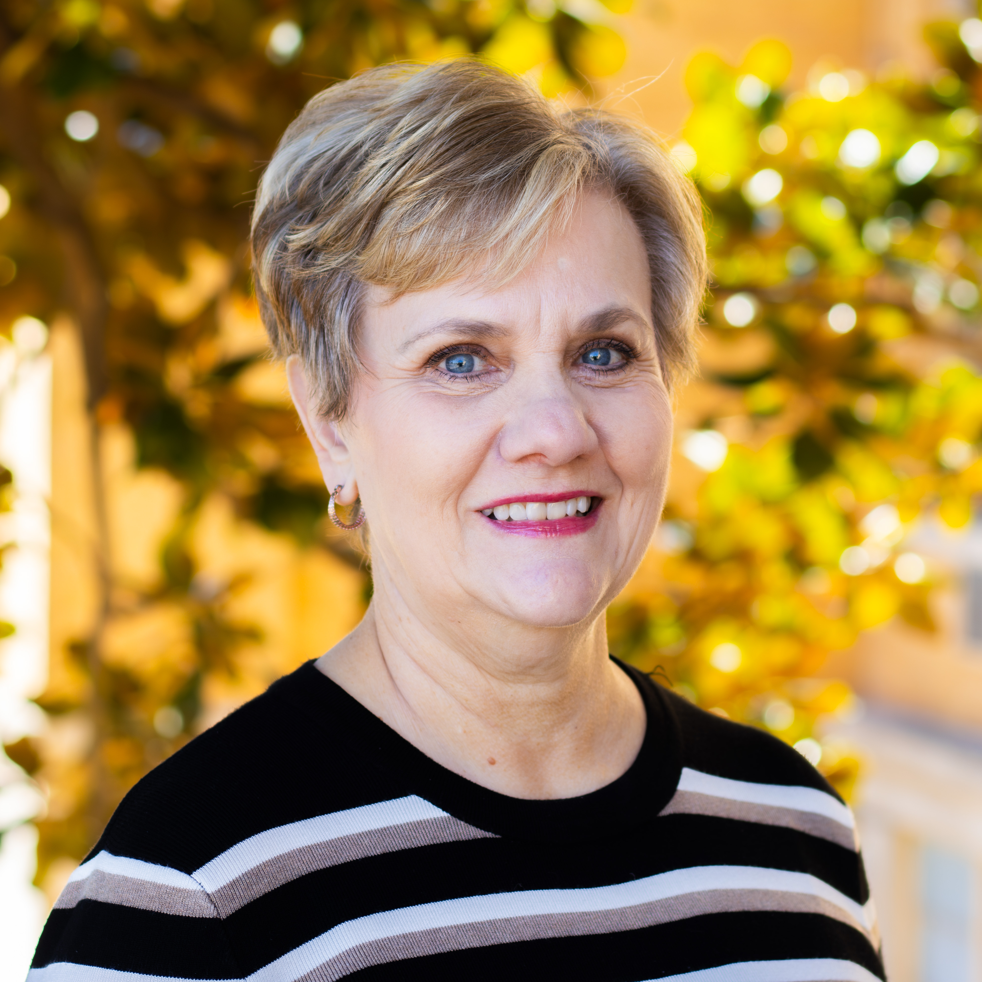 A photo of Sharon Greene smiling in a black striped shirt