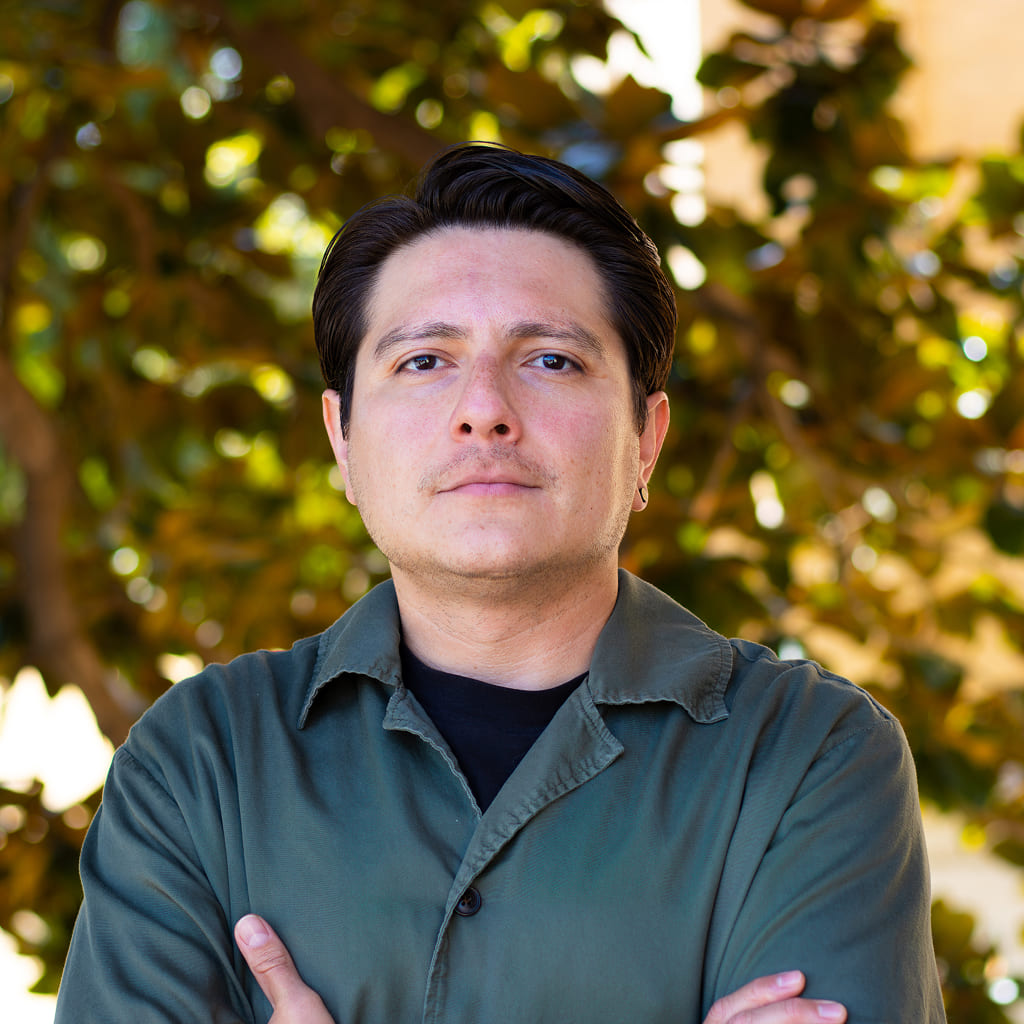A man standing in front of a tree with crossed arms