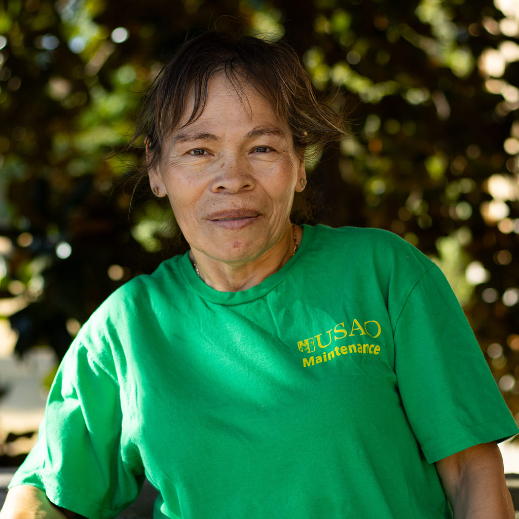 A woman standing in a green t-shirt and smiing