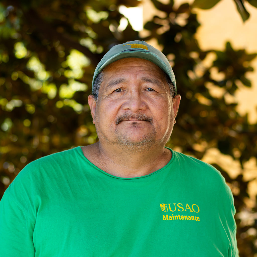 A man in a green t-shirt standing in front of a tree