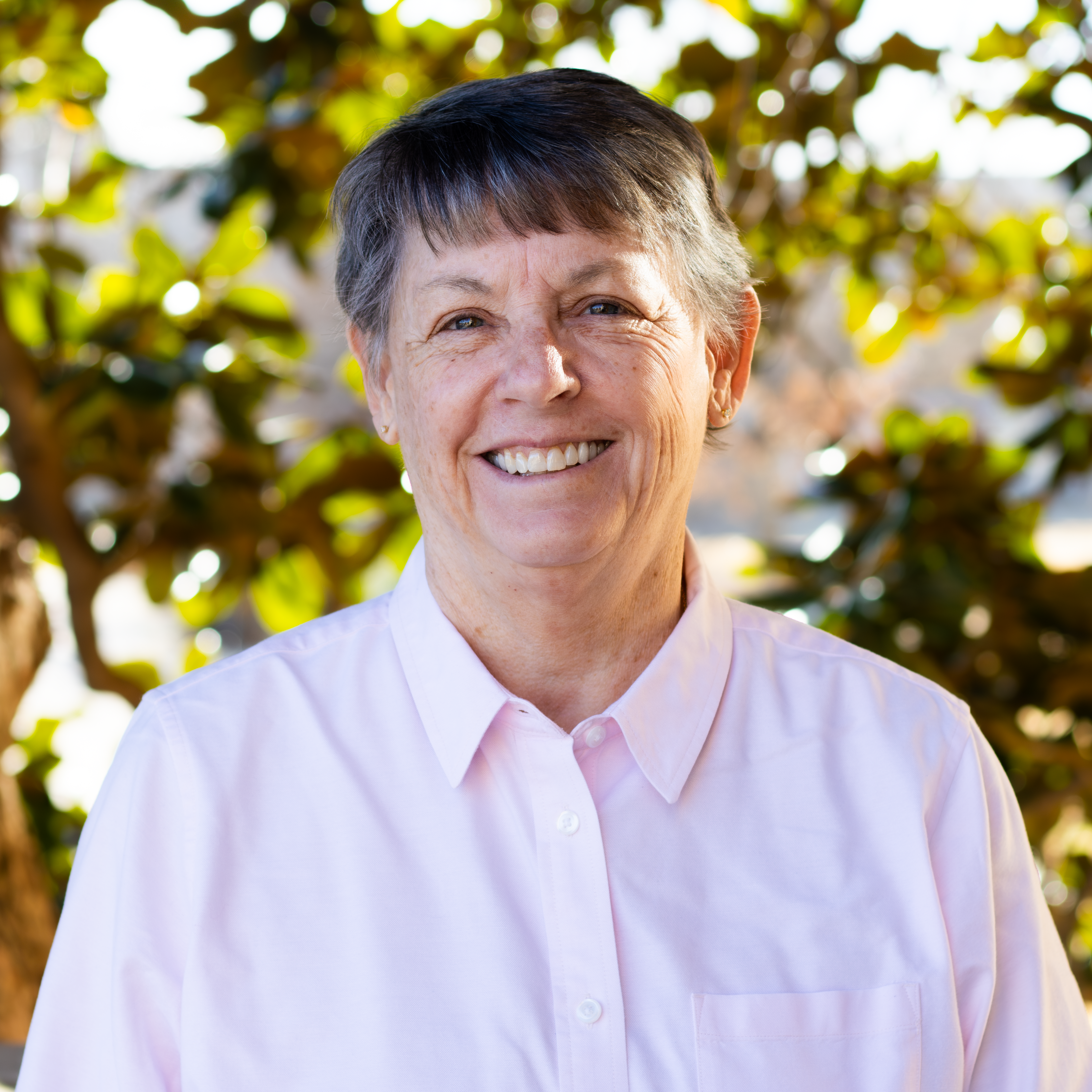 Woman smiling in a pink button up shirt